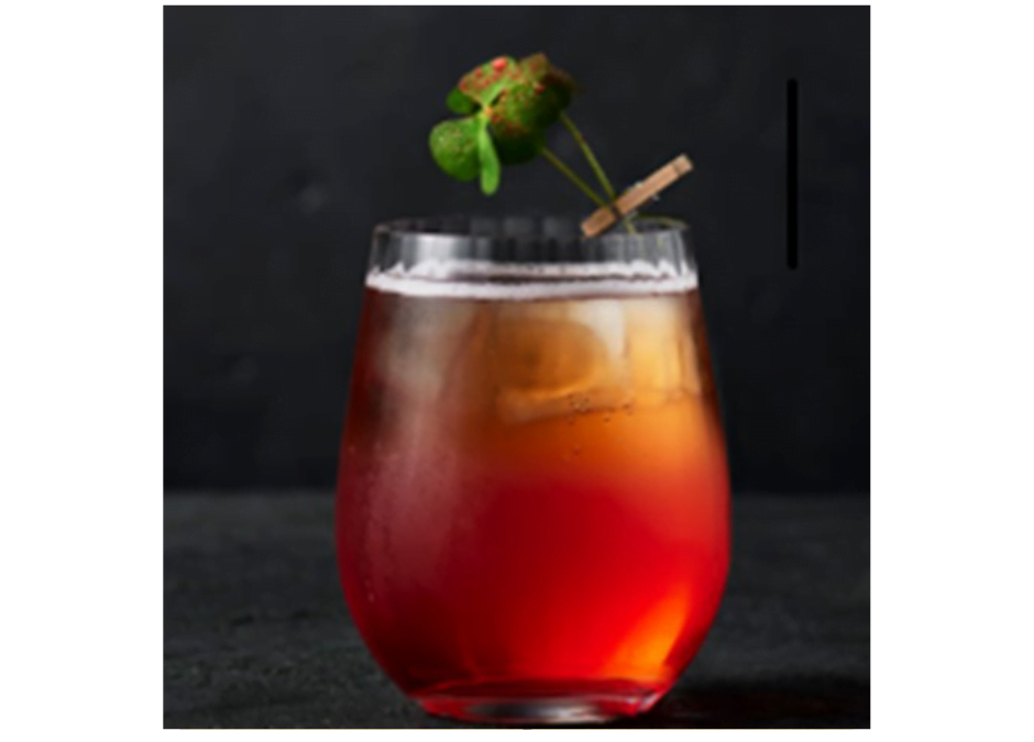 Een sfeervol glas met de alcoholvrije cocktail Flower of Jasminum. Het geheel heeft de sfeervolle kleur van thee en is gegarneerd met een takje jasmijn.